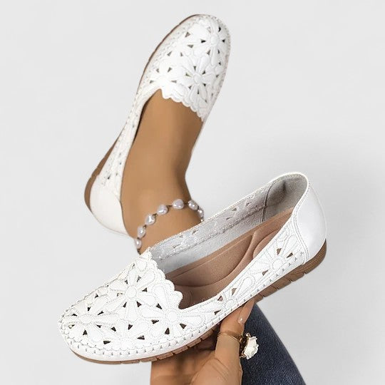 Top view of women's perforated slip on flats displaying all-over cutout pattern and elastic side panels