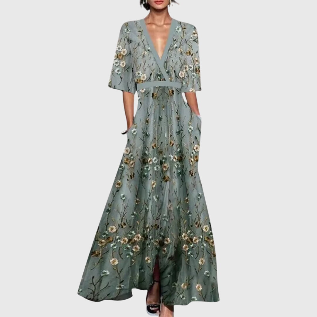 Front view of floral maxi dress showing deep V-neckline, three-quarter sleeves, and scattered blue floral pattern intensifying toward hem