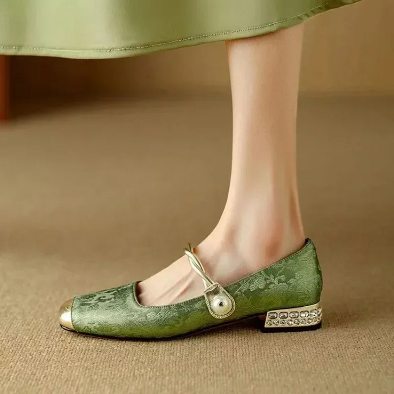 Close-up view of pearl-embellished ankle strap and glitter block heel detail on Mary Jane shoes