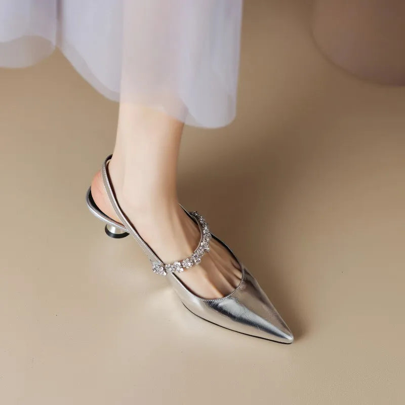 Close-up view of crystal-embellished instep strap on metallic slingback heels with pointed toe silhouette