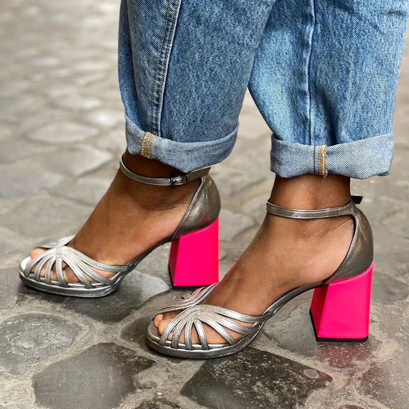 Colorful shiny sandals with buckle and thick heel featuring metallic silver straps, open toe design, and vibrant pink block heel worn with rolled denim jeans