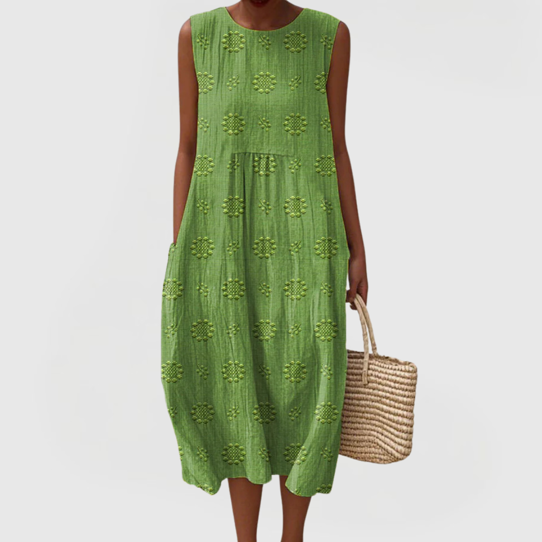Woman wearing green sleeveless linen midi dress with embroidered geometric detailing and side pockets