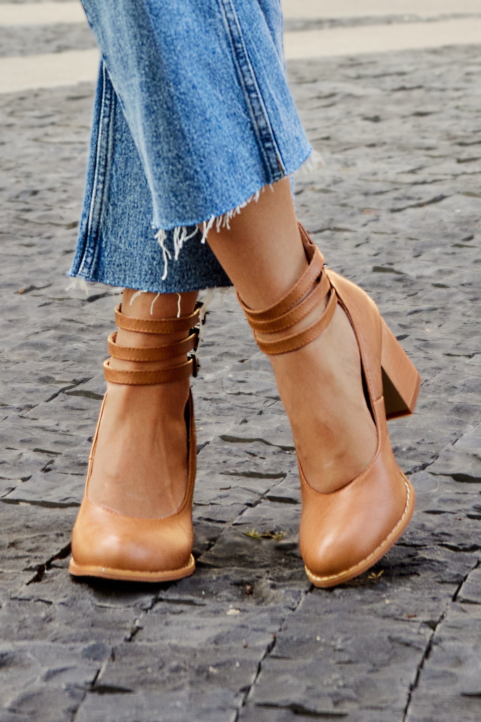 Detail shot of thick block heel and ankle strap buckle closure on smooth sandals