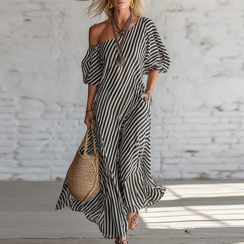 Back view of striped maxi dress showing flowy drape and one shoulder construction detail