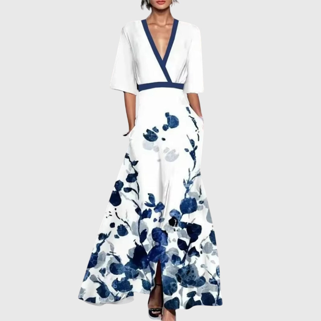 Woman wearing white floral maxi dress with blue botanical print and navy contrast trim at neckline and waist