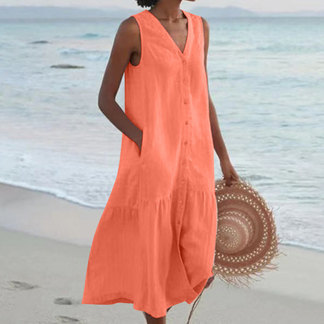 Woman walking in sleeveless button-front linen beach dress on sandy beach setting