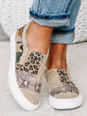 Close-up of women's slip-on loafers showing elastic side gores and frayed canvas edges with animal print panels