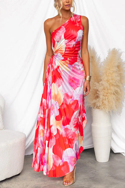 Flowing maxi length pleated summer dress featuring asymmetric hemline and bold print