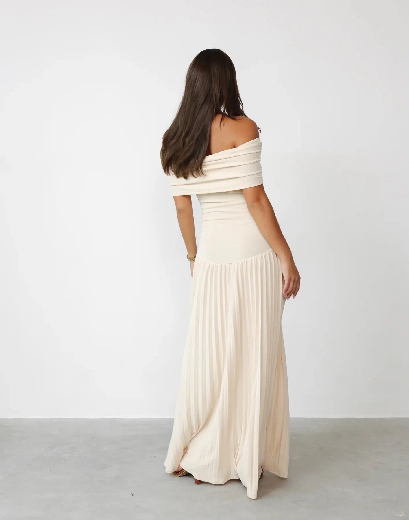 Side angle of pleated maxi dress with defined waist and ankle length hem