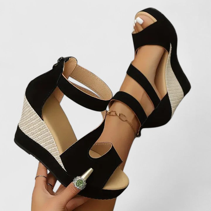 Close-up view of black orthopedic wedge sandals showing adjustable elastic strap configuration and textured heel