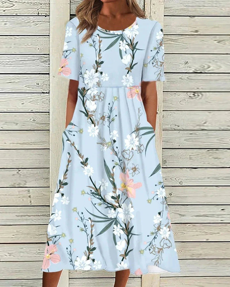 Grace wearing a Printed Floral Midi Dress in light blue with white and pink botanical print, round neckline, and short sleeves