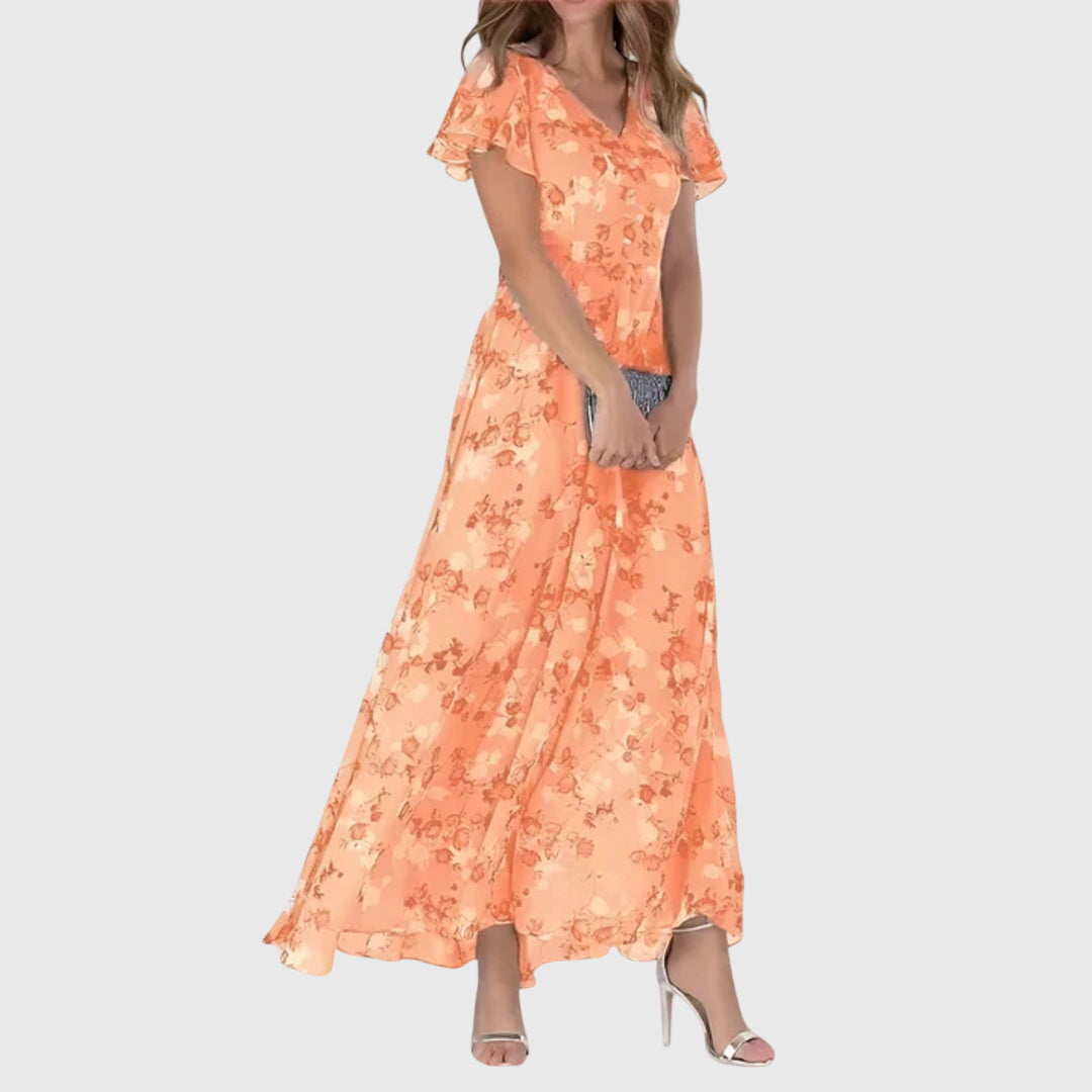 Harper floral maxi dress in coral peach with flutter sleeves and V-neckline worn with heeled sandals