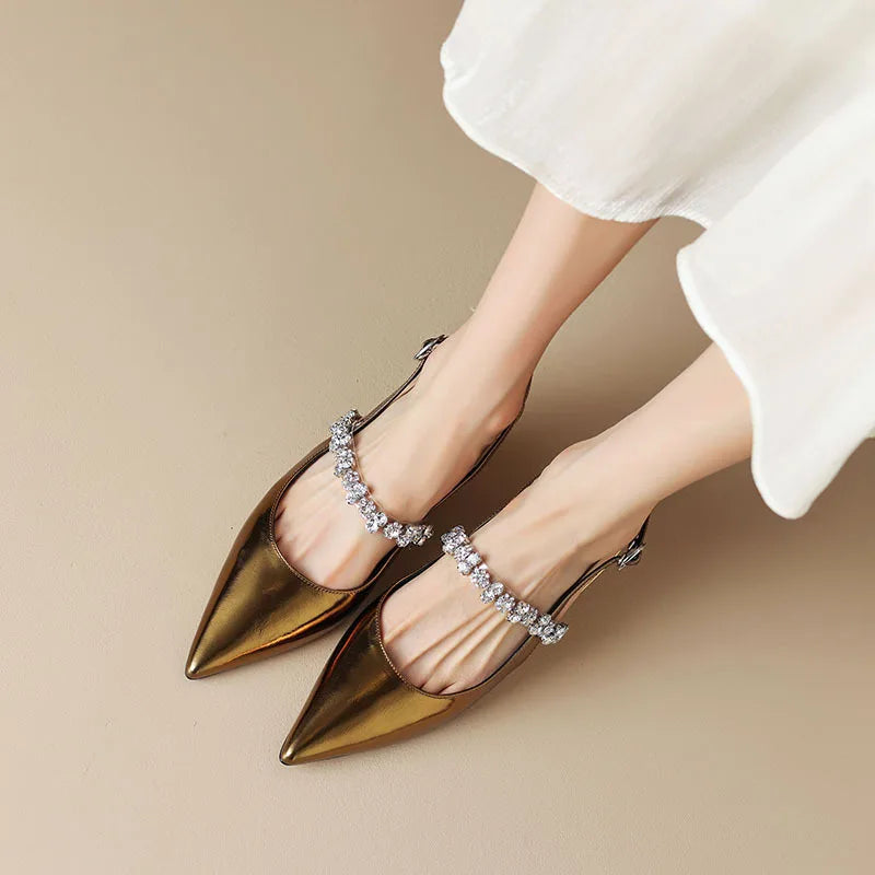 Close-up of sparkling crystal detail on instep strap of metallic pointed toe slingback pumps