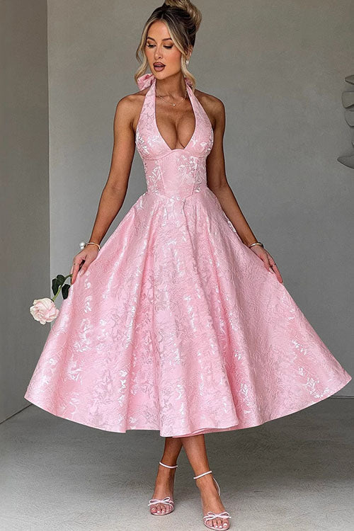 Woman wearing pink halterneck midi dress with deep V-neckline and full flared skirt for wedding guest occasions