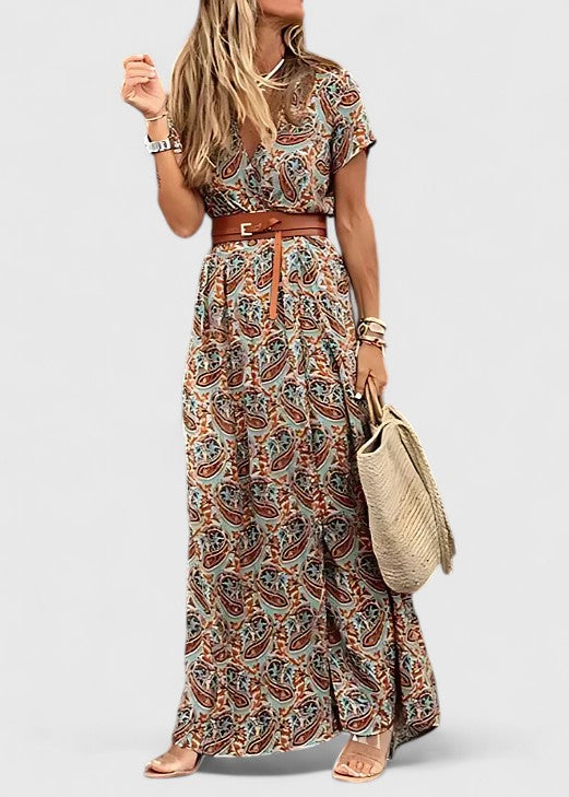Full-length maxi boho dress in navy paisley print styled with gold sandals and straw bag