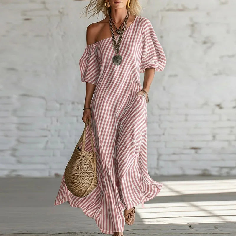 Woman wearing pink and white striped one shoulder puff sleeve dress with maxi length and flowy silhouette