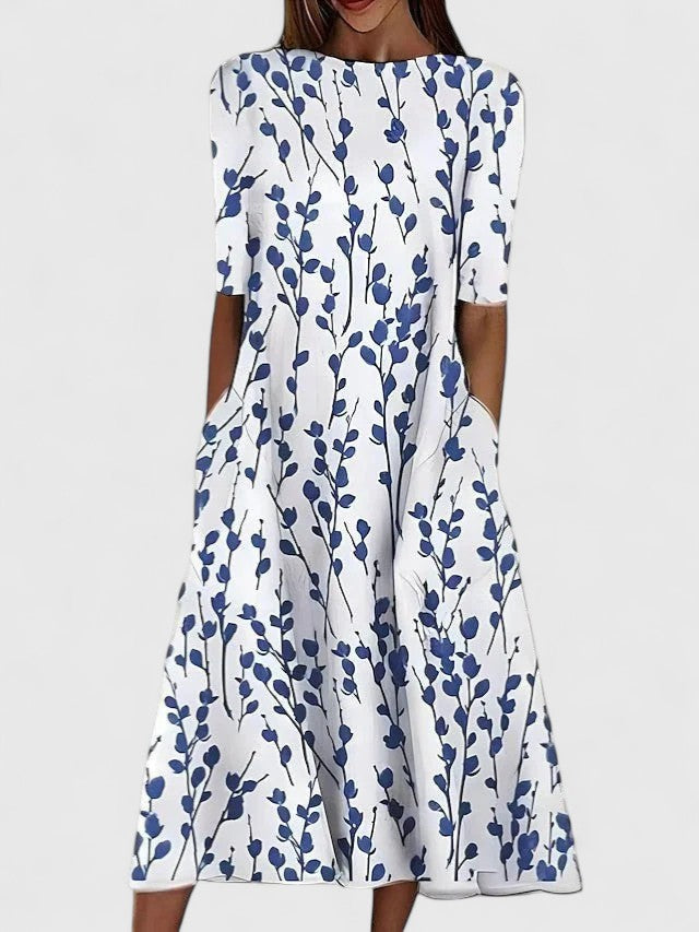 Woman wearing a white floral midi dress with blue botanical print and elbow-length sleeves