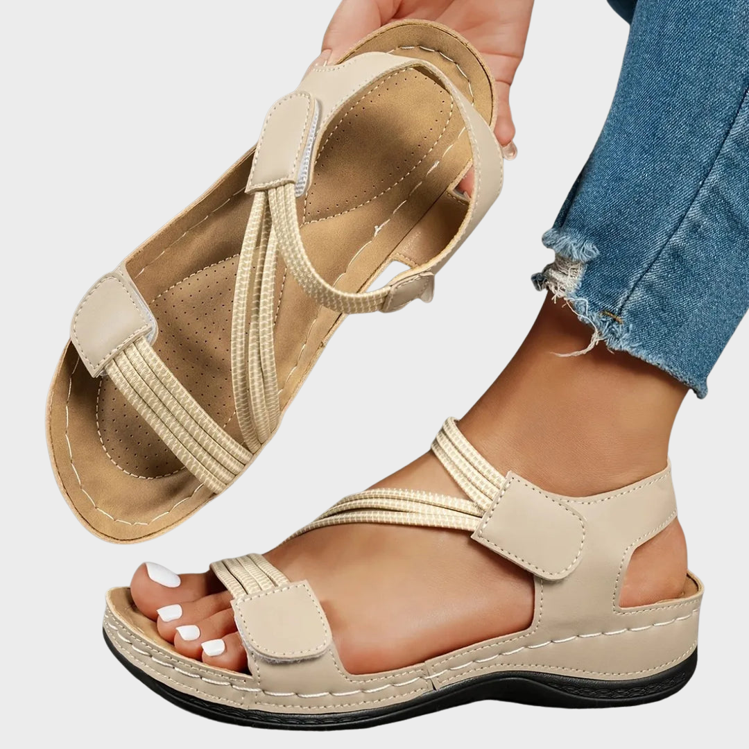 Sophie wearing beige women's casual sandals with adjustable straps and cushioned sole featuring elastic crossover bands and hook-and-loop ankle closure